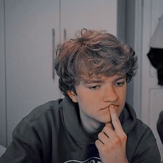 a young man sitting at a table with his finger in his mouth