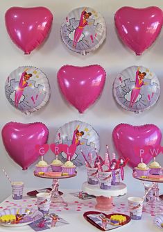 a table topped with pink heart shaped balloons and cupcakes on top of plates