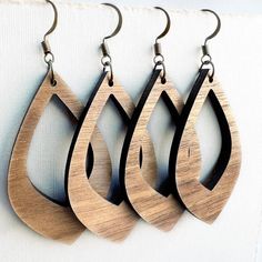 three wooden earrings hanging from hooks on a wall