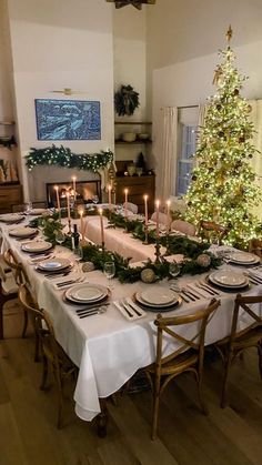 a dining room table is set for christmas dinner with candles and plates on the table