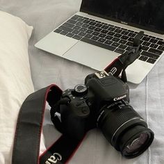 a camera sitting on top of a bed next to a laptop