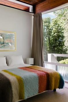 a bedroom with a large window overlooking the trees