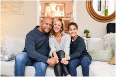 a woman and two children sitting on a white couch in front of a christmas tree