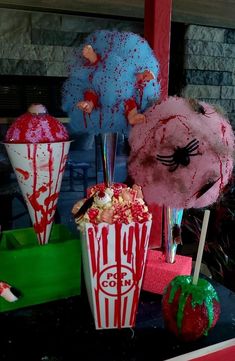 three popcorn buckets decorated with candy and splatters