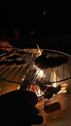 some food is cooking on an open grill in the dark with flames coming from it