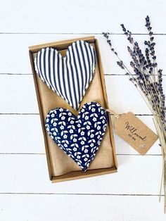 two heart shaped cushions in a box next to some dried lavenders and a tag