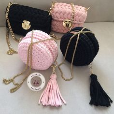 three purses with tasselled handles, one in pink and one in black