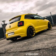 a yellow car parked in front of a fence