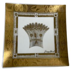 a gold and white plate with an image of a peacock in the center on it