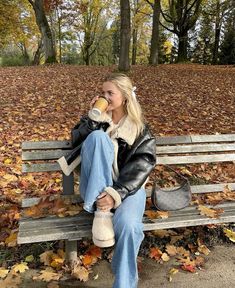 a woman sitting on a park bench drinking coffee