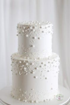 a three tiered white wedding cake with pearls