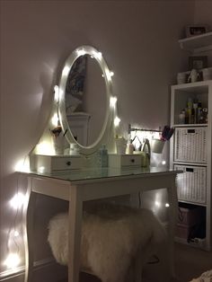 a white vanity with lights on it and a mirror in the corner next to it