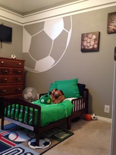 a child's bedroom with a soccer themed wall decal and green bedding