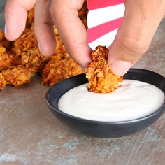 a person dipping some food into a bowl