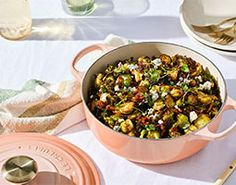 a pot filled with food sitting on top of a table next to utensils