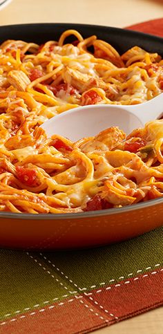 a skillet filled with pasta and cheese on top of a table next to plates