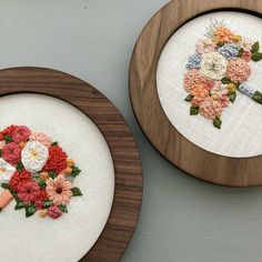 two wooden frames with flowers on them, one has a cross stitch bouquet in it