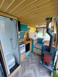 the interior of a camper van with wood flooring and colorful decor on the walls