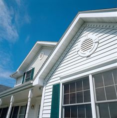 a white house with green shutters under a blue sky