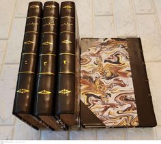 four books sitting on top of each other in front of a white tile flooring