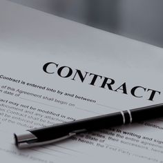 a pen sitting on top of a paper with the word contract written in black ink