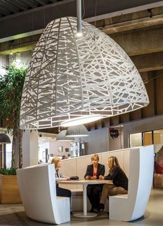 two women sitting at a table in front of a large light hanging from the ceiling