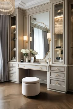 an elegant dressing room with white furniture and chandelier