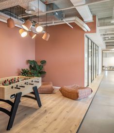 an office with pink walls and wooden flooring, foo - pong table in the foreground