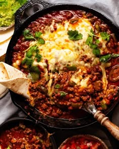 a skillet filled with chili, cheese and tortilla bread