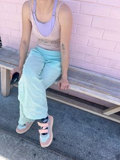 a woman sitting on a wooden bench wearing pink and blue shoes with her hands in her pockets