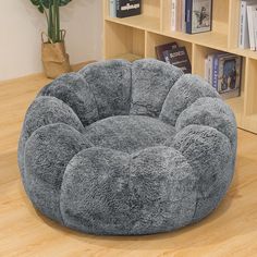 a large gray dog bed on top of a wooden floor next to a book shelf