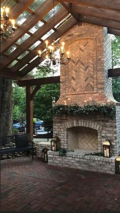 an outdoor fireplace in the middle of a patio with lights hanging from it's roof