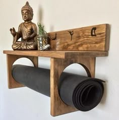 a wooden shelf with a buddha statue on it and a roll of yoga mat underneath