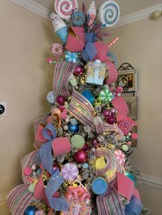 a decorated christmas tree with pink, blue and white ornaments on it's top