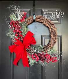 a wreath with red berries and greenery hangs on the front door