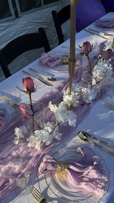 the table is set with pink and white flowers, silverware, and napkins