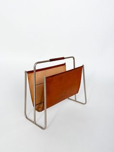 a metal and leather magazine rack on a white background