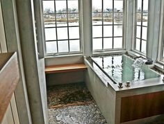 a bath tub sitting in the middle of a room next to two windows and a bench