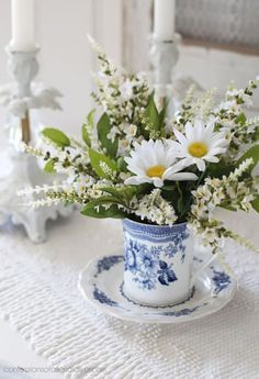 a blue and white teacup with daisies in it