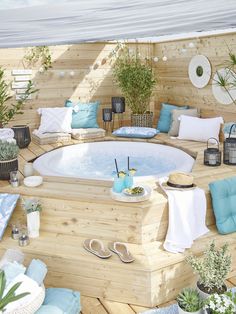 an outdoor hot tub surrounded by plants and other decorations on a deck with blue cushions