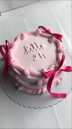 a birthday cake with pink frosting and red ribbon