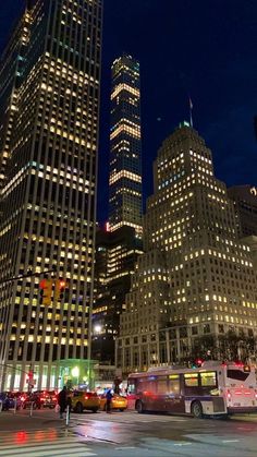 the city is lit up at night and there are many cars driving down the street