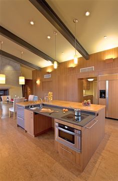 a kitchen with an island, stove and refrigerator freezer in the center is lit by recessed lights