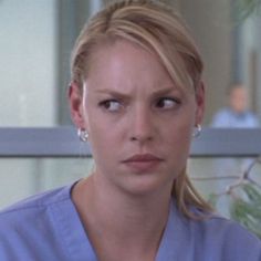 a woman in scrubs is looking at the camera with serious expression on her face