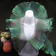 a white mannequin with green hair and flowers next to it on a black background