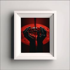 two hands holding up a red object in front of a white frame