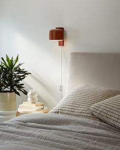 a bedroom with a bed, lamp and potted plant on the nightstand next to it