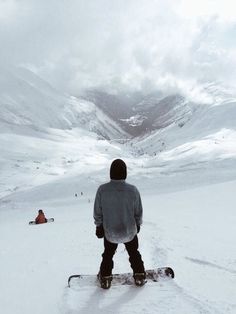 a man riding a snowboard down the side of a snow covered slope