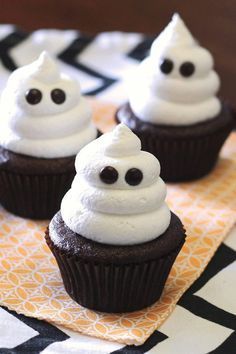 three cupcakes with white frosting and chocolate eyes