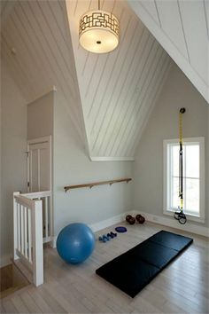 an exercise room with yoga mat, exercise balls and gym equipment